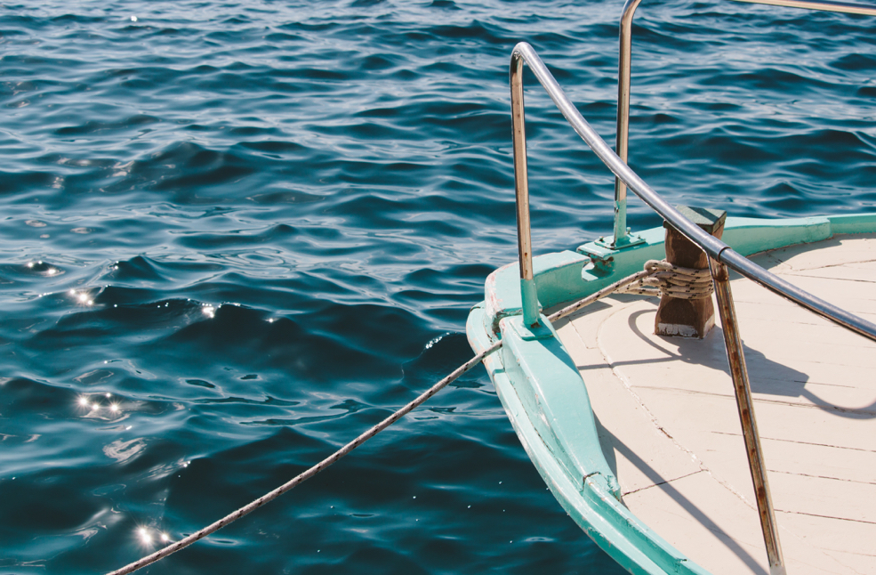 Part of a boat with an anchor rope in the ocean.